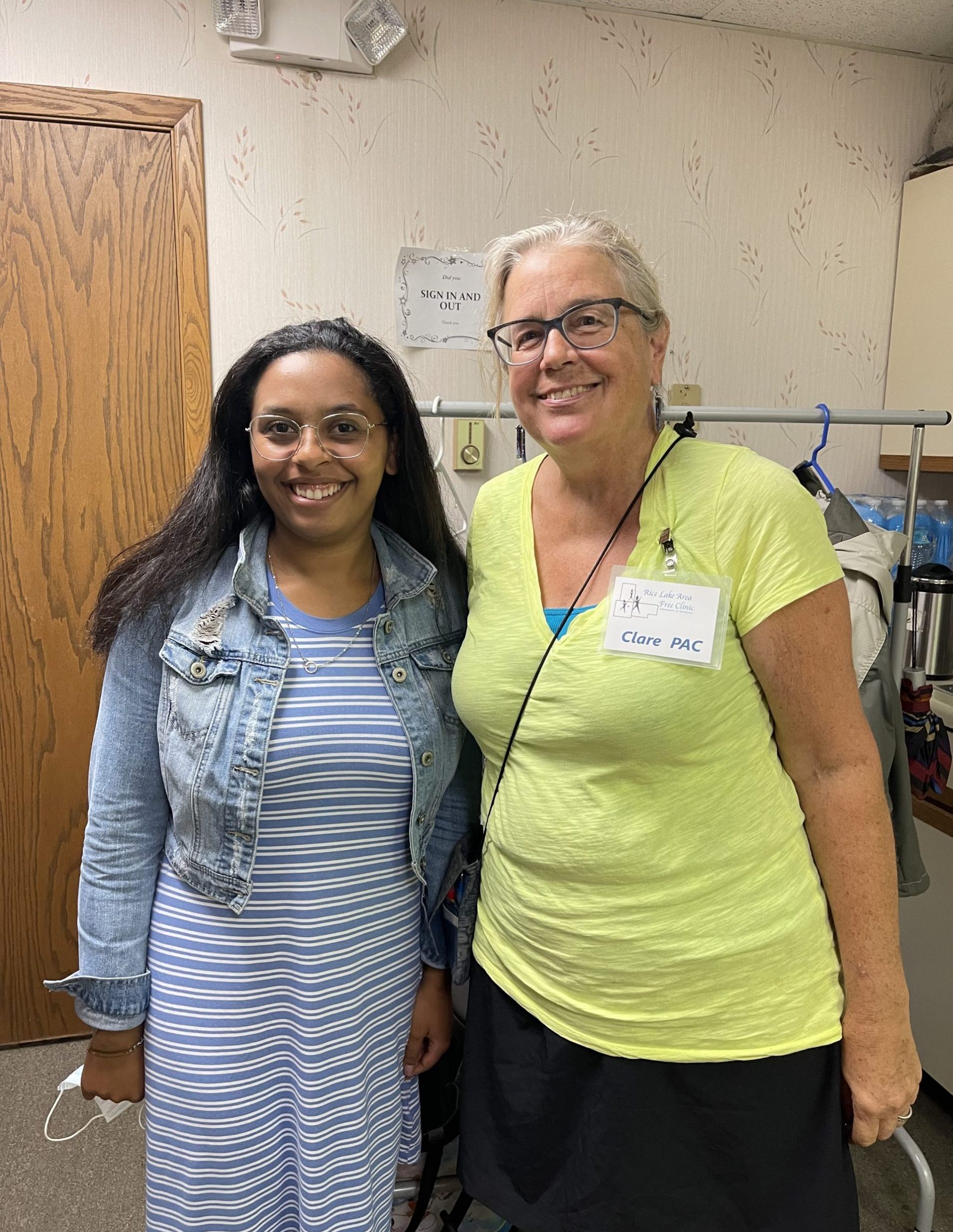A young woman and an older woman smile as they stand, posing for the camera