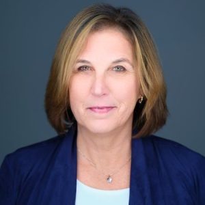 A woman with short brown hair in a blue blazer smiling