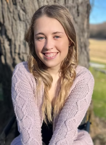 A woman in a pink cable-knit sweater smiling
