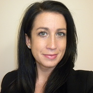 A woman smiling with long black hair in a black blazer