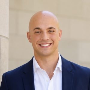 A man smiling with no hair in a blue blazer